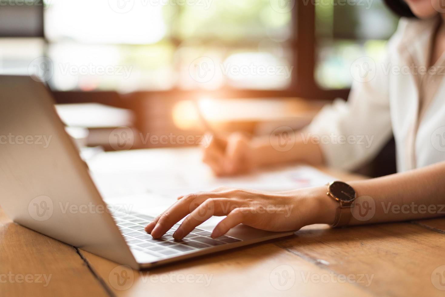 primo piano di una donna che digita la tastiera sul computer portatile nella caffetteria foto