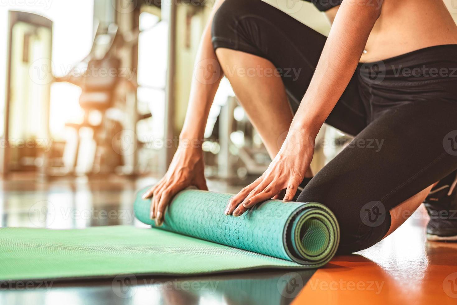 primo piano di donna sportiva pieghevole materasso yoga in palestra fitness sportiva foto