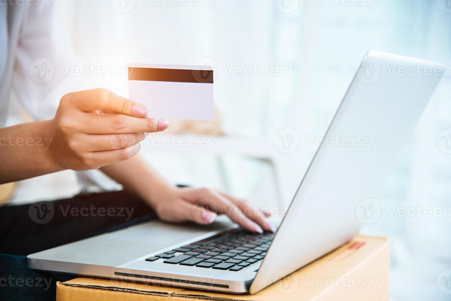 mani di donna che tengono la carta di credito per lo shopping online foto