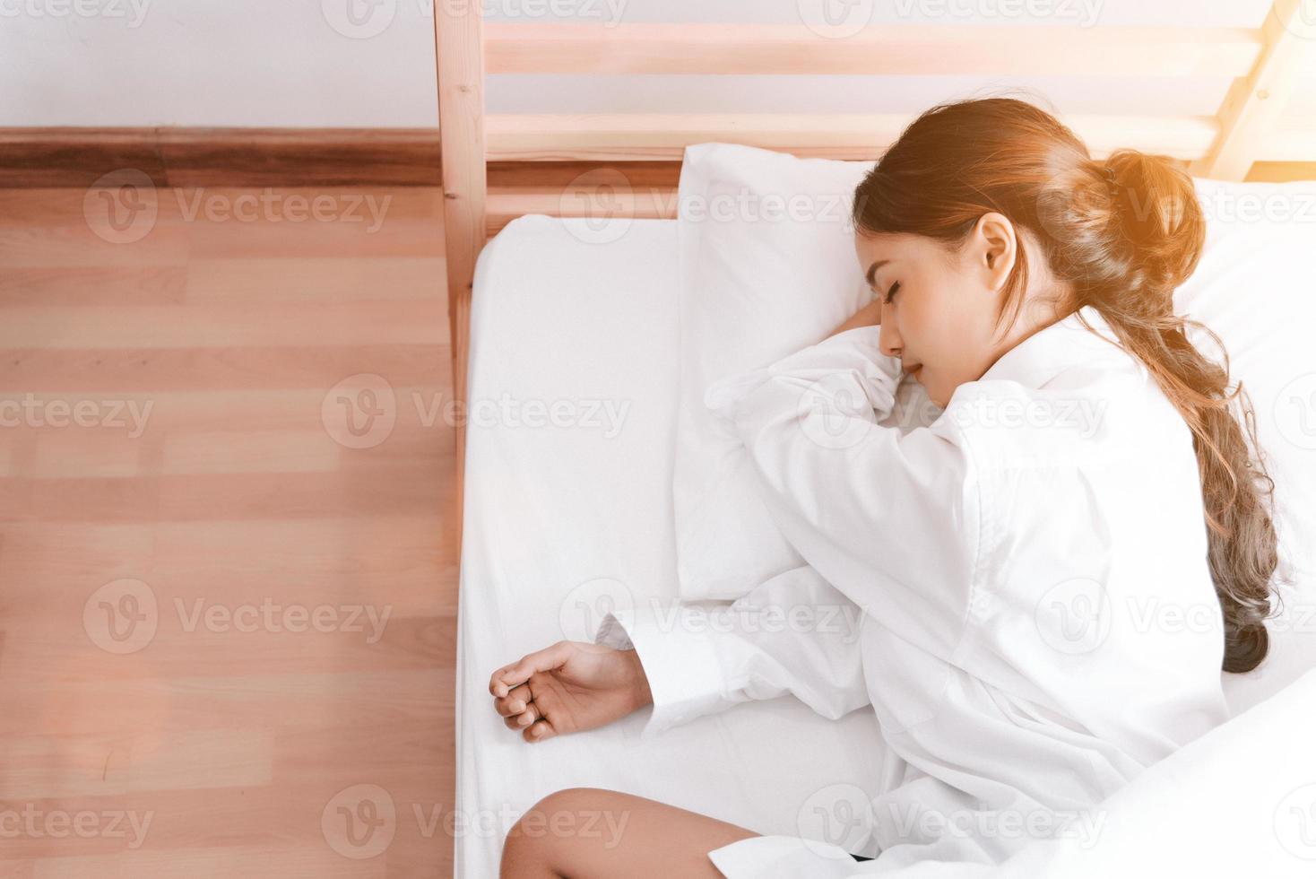 giovane donna asiatica che dorme sul letto bianco al mattino foto