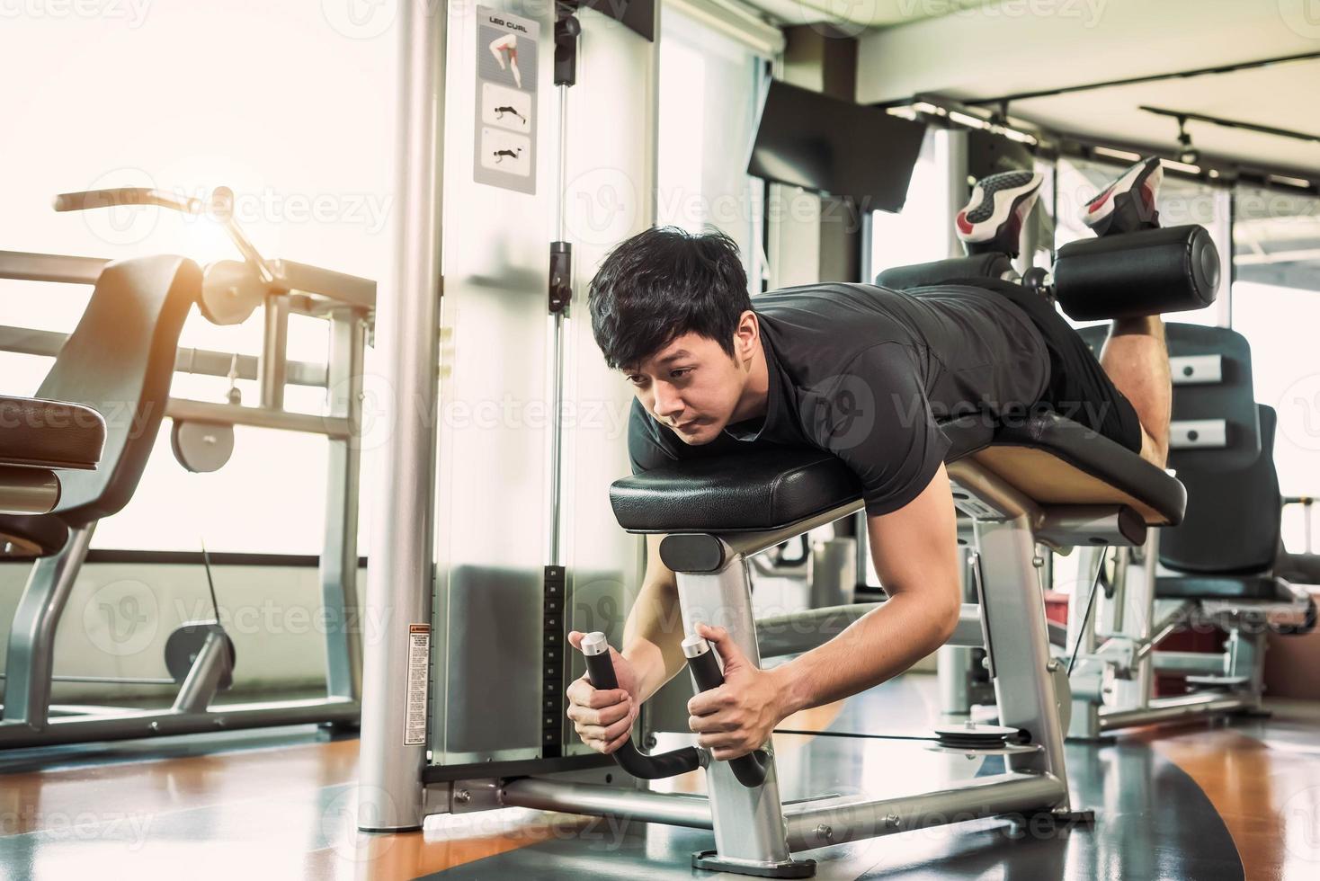 uomo sportivo asiatico che allunga e solleva peso con due gambe foto