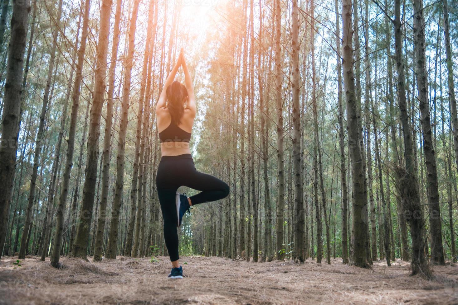 bella giovane donna asiatica in piedi e facendo yoga nella foresta foto