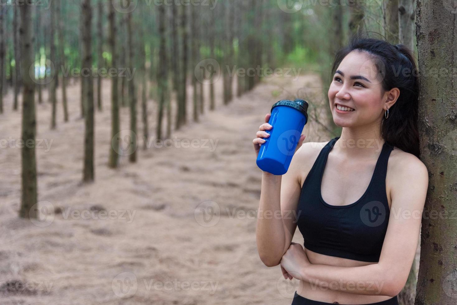 bellezza donna asiatica sportiva che riposa e tiene acqua potabile foto