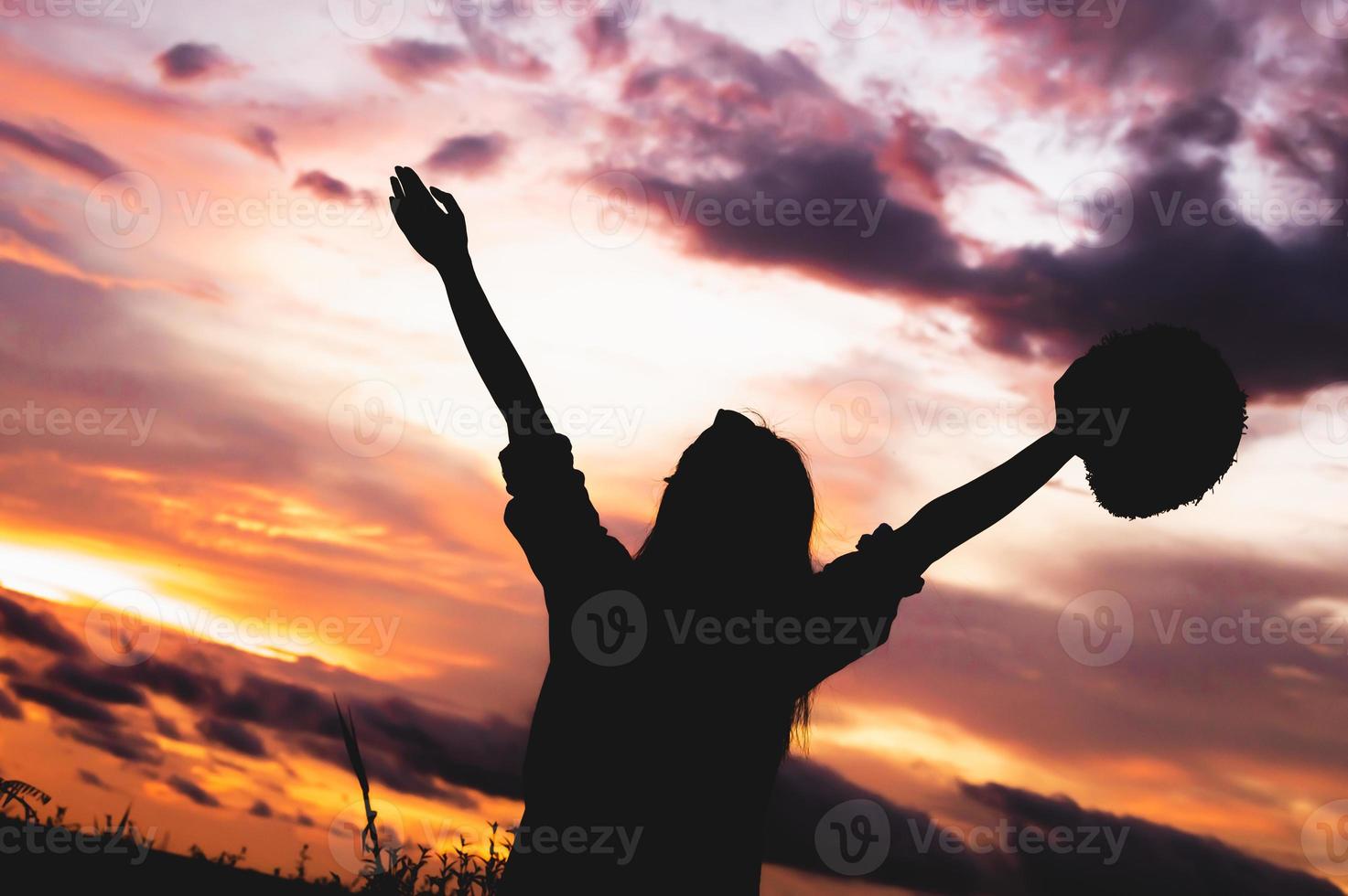 silhouette di donna felice a braccia aperte sotto l'alba foto