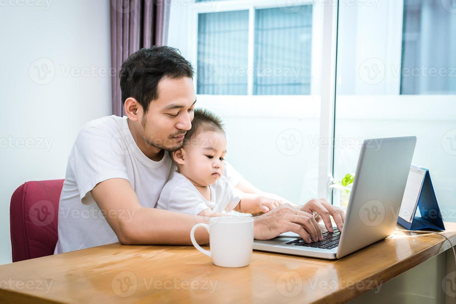 papà single e figlio che usano felicemente il laptop insieme foto