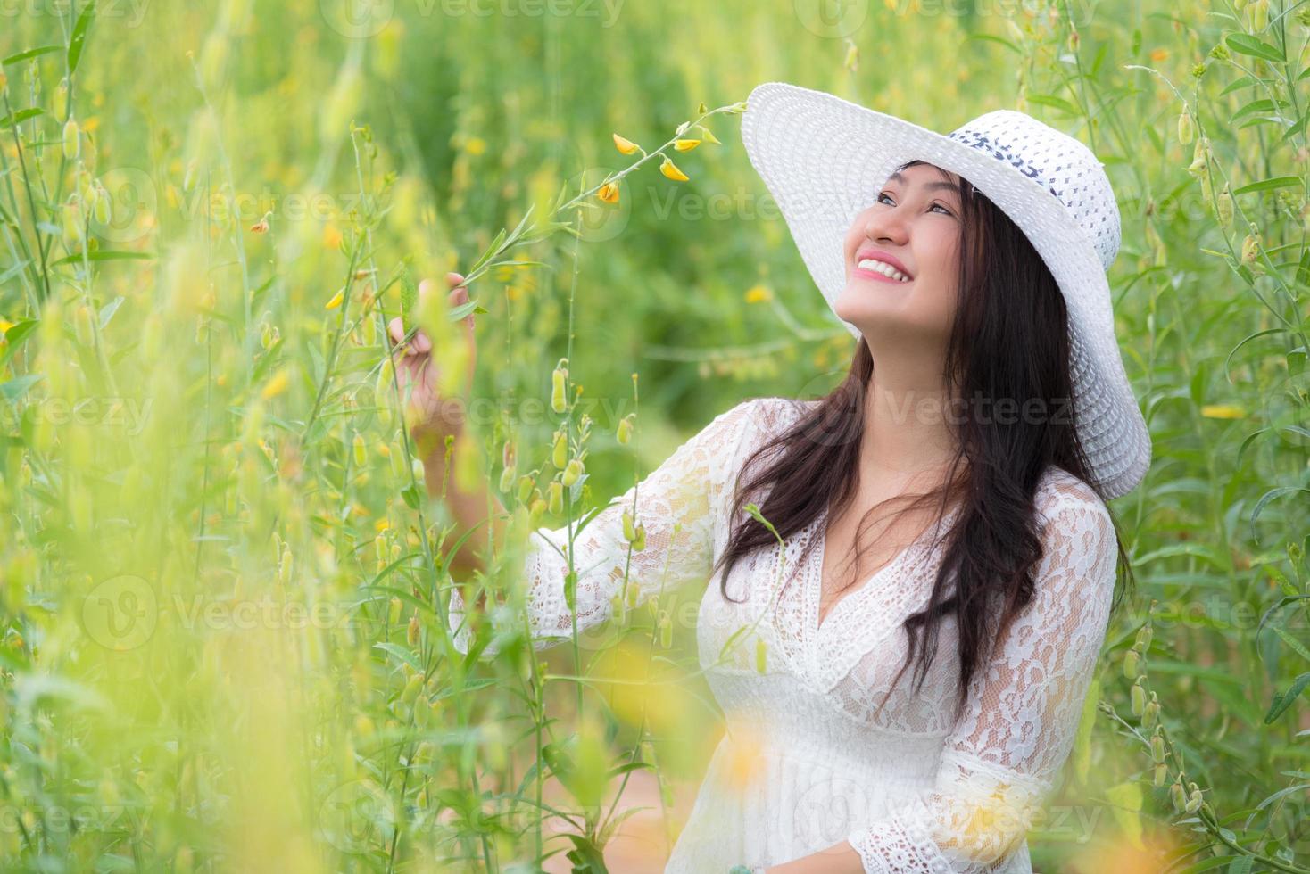 donna asiatica in abito bianco ala cappello che cammina nel campo di fiori di colza foto
