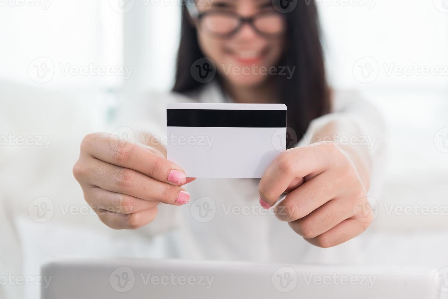 la giovane donna asiatica usa la carta di credito per lo shopping online con il laptop foto