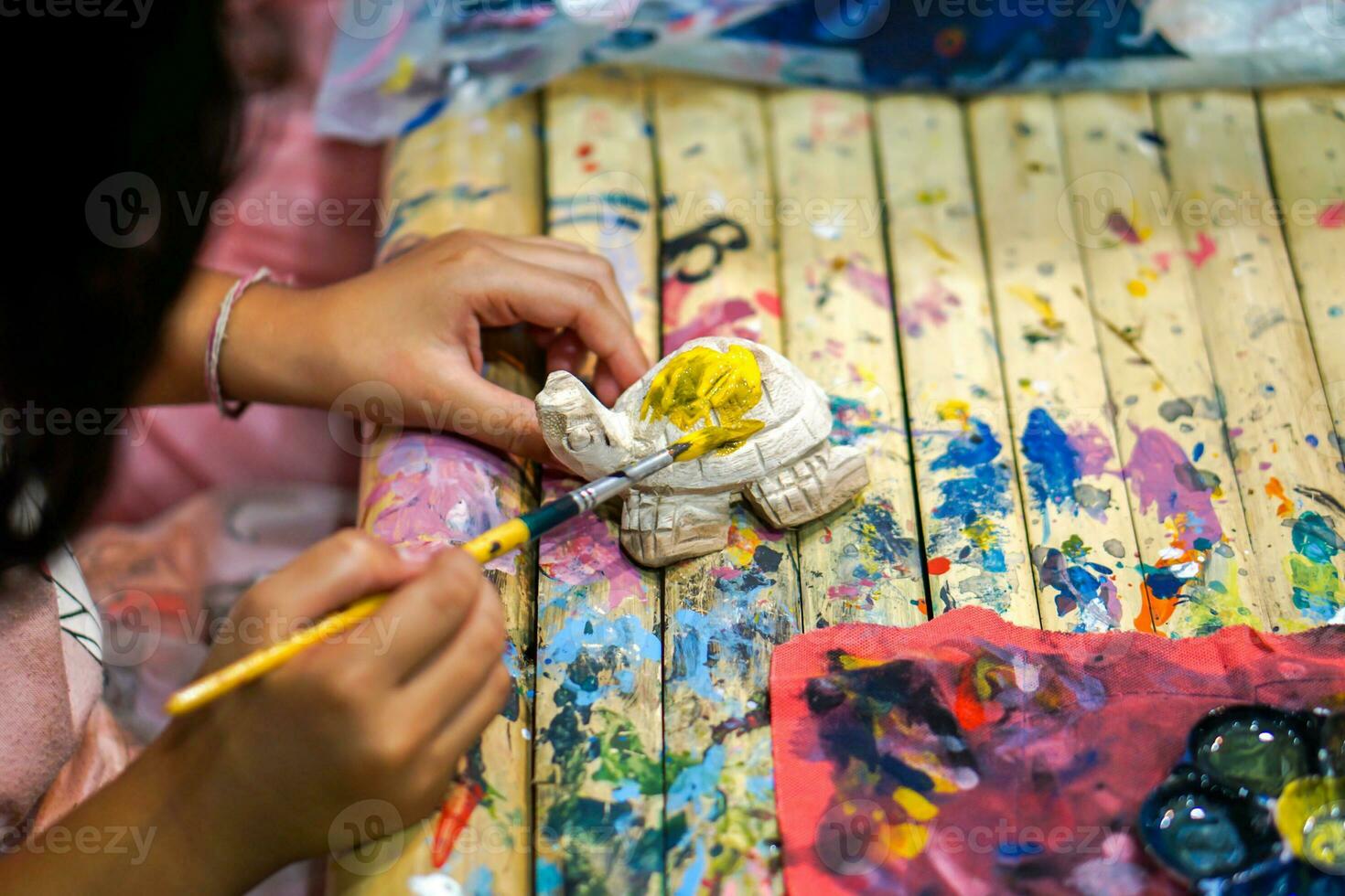 primo piano mani di studenti d'arte che tengono lo studio del pennello e l'apprendimento della pittura su legno bambola animale nell'aula d'arte. foto