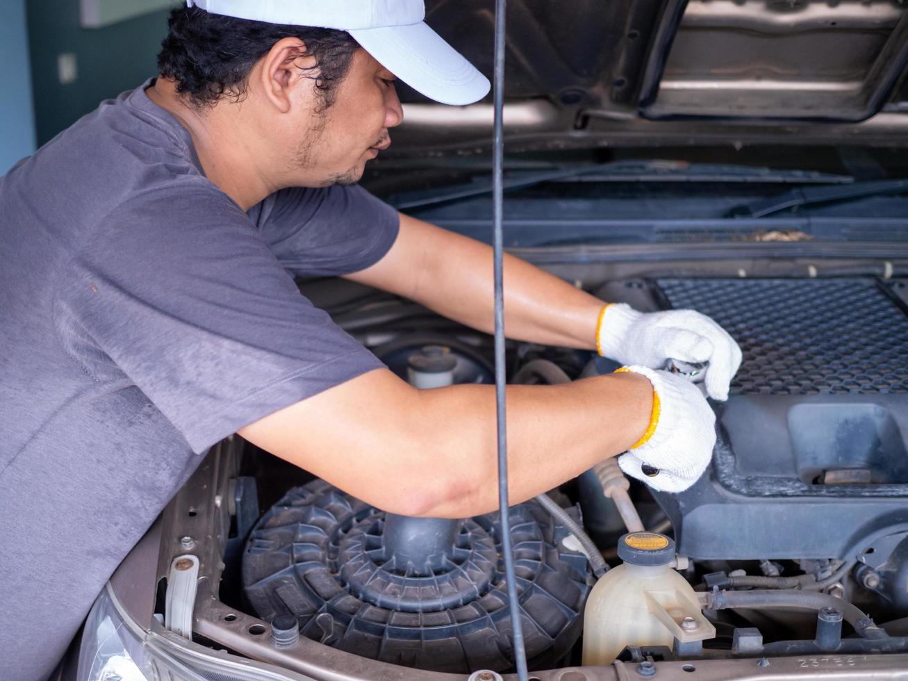 meccanico che tiene in mano una chiave inglese durante la riparazione di un'auto. foto