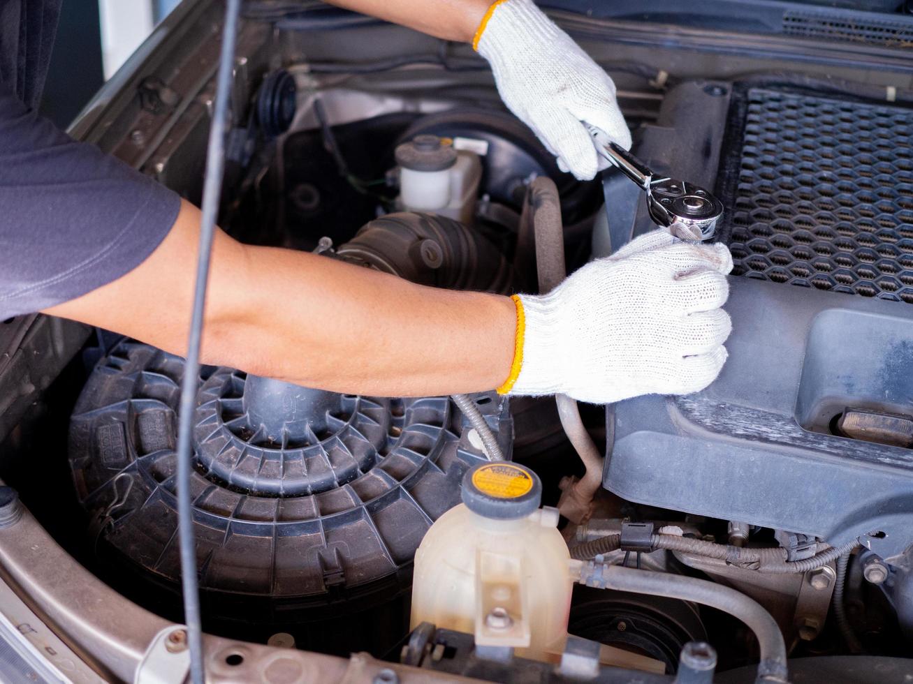 meccanico che tiene in mano una chiave inglese durante la riparazione di un'auto. foto