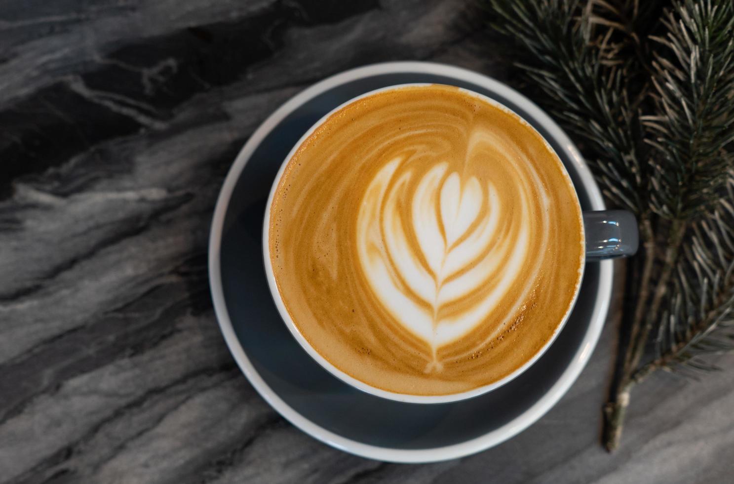 caffè d'arte latte in tazza sul tavolo di marmo nella caffetteria foto