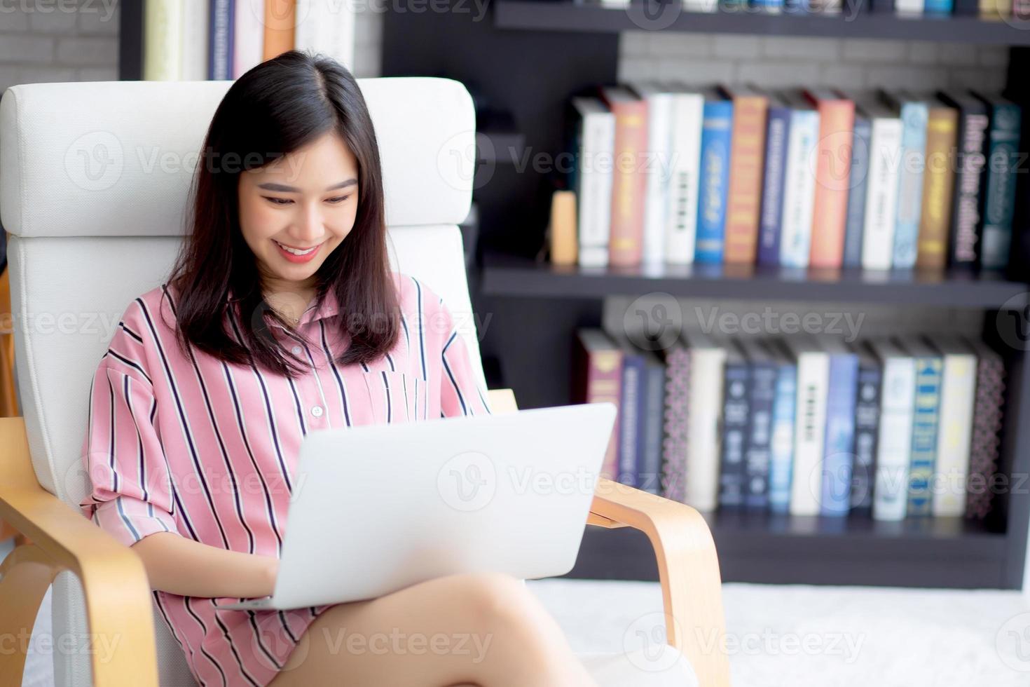 giovane donna asiatica che lavora computer portatile online seduto sulla sedia. foto