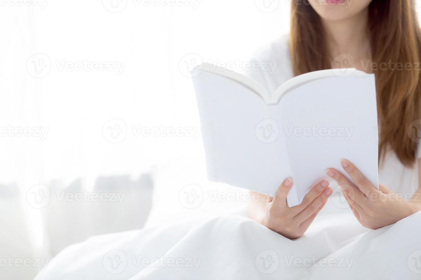 la giovane donna asiatica si rilassa leggendo il libro seduto sulla camera da letto. foto