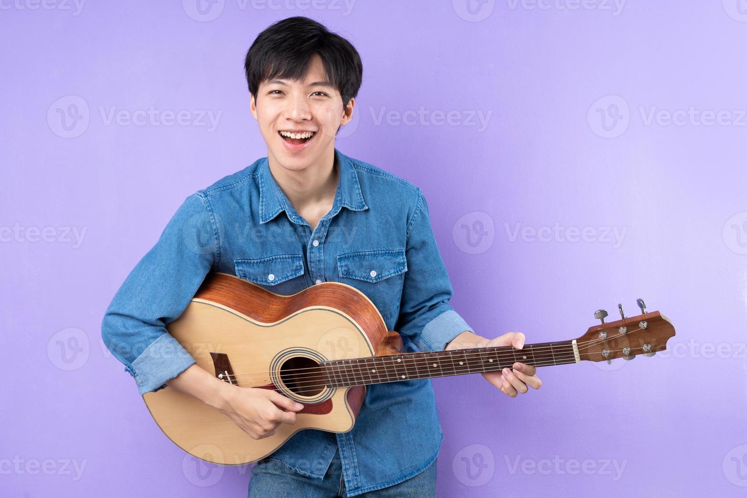 ritratto di uomo asiatico in camicia blu in posa su sfondo viola foto