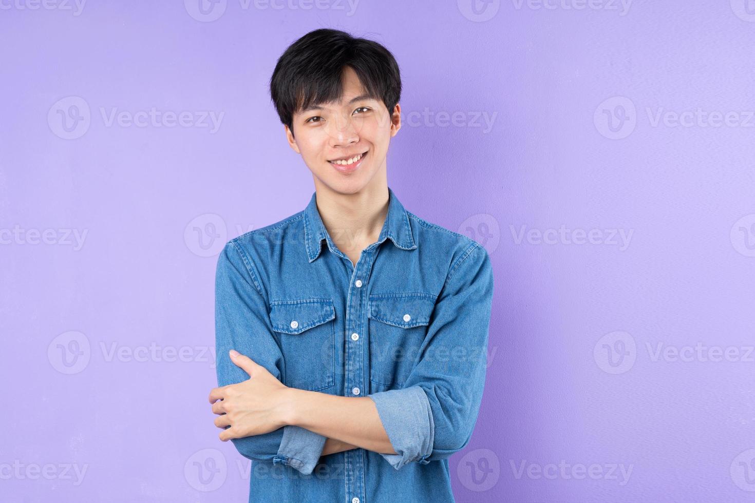 ritratto di uomo asiatico in camicia blu in posa su sfondo viola foto