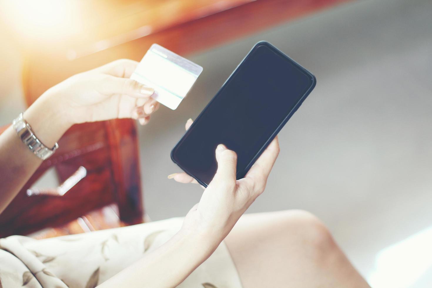 donna che usa il telefono e la carta di credito che fa shopping online foto