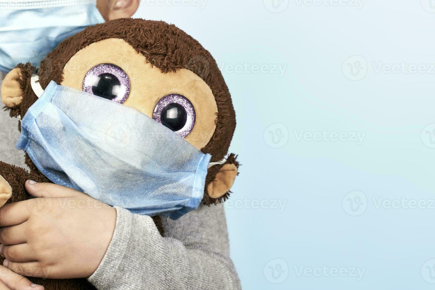 poco prescolastico ragazzo giocando con il suo giocattolo scimmia nel medico viso maschera foto