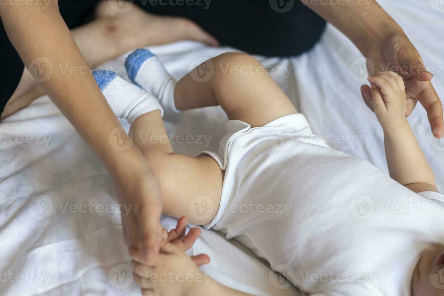 bambino massaggio. mamma fare ginnastica con ragazzo. mammina massaggio carino bambino ragazzo. in movimento del bambino gambe per Aiuto alleviare stipsi. giovane madre fare esercizi e movimenti per stimolare del bambino viscere. foto