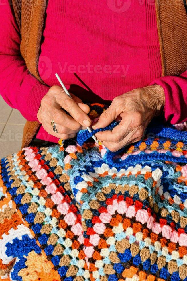 un più vecchio donna è maglieria un' colorato uncinetto coperta foto