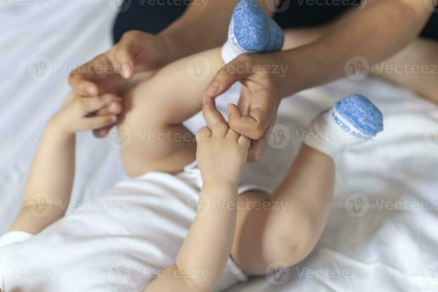 bambino massaggio. mamma fare ginnastica con ragazzo. mammina massaggio carino bambino ragazzo. in movimento del bambino gambe per Aiuto alleviare stipsi. giovane madre fare esercizi e movimenti per stimolare del bambino viscere. foto