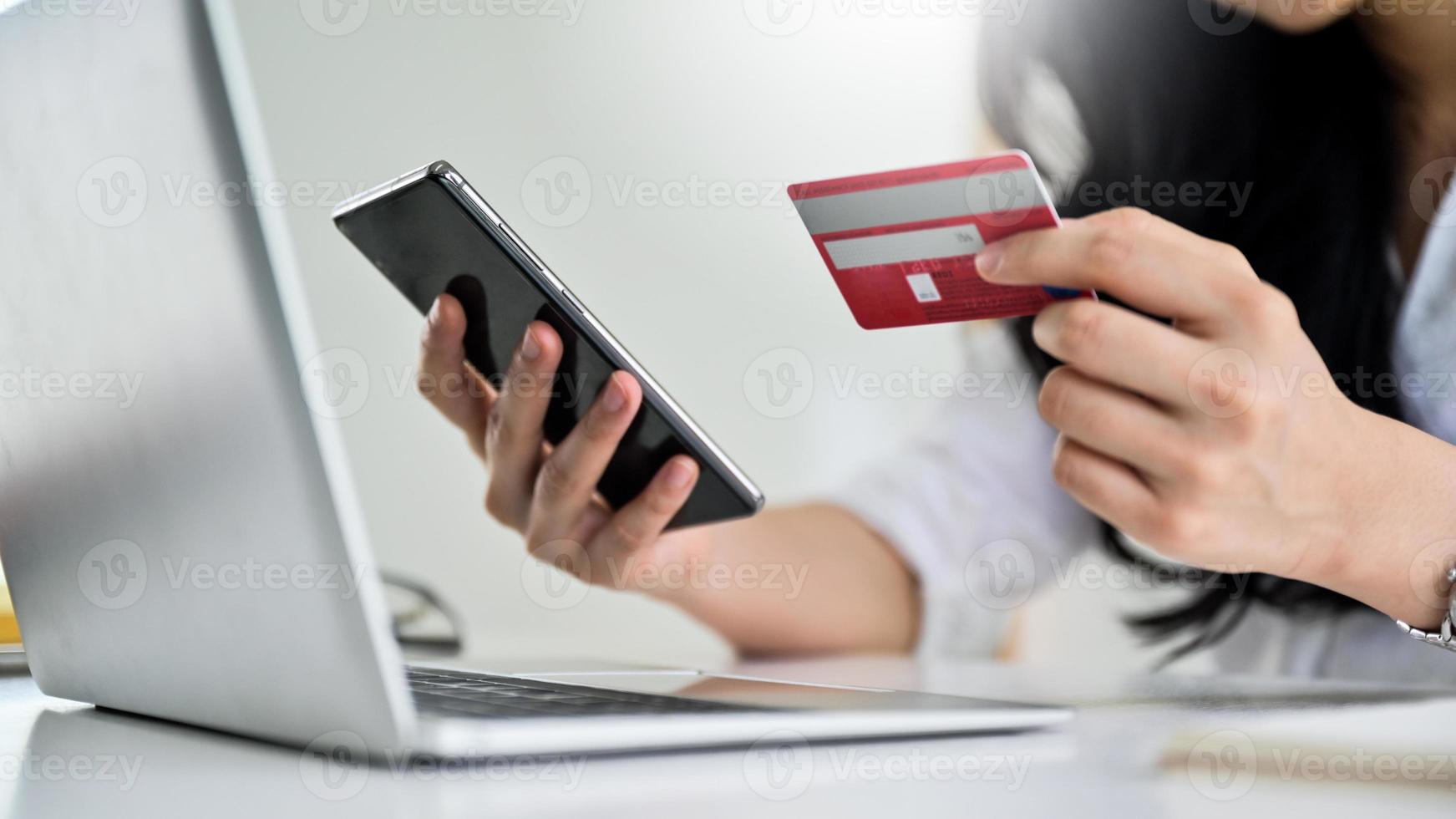 giovane donna in possesso di carta di credito e smartphone con laptop, foto