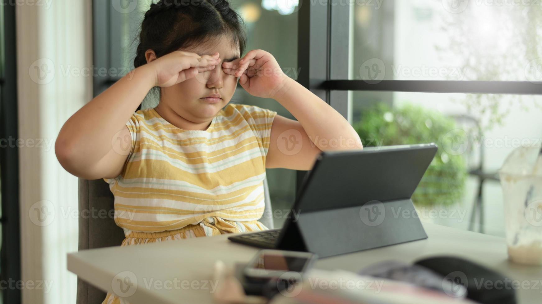 la ragazza asiatica del bambino chiude gli occhi per riposare dall'uso del tablet. foto