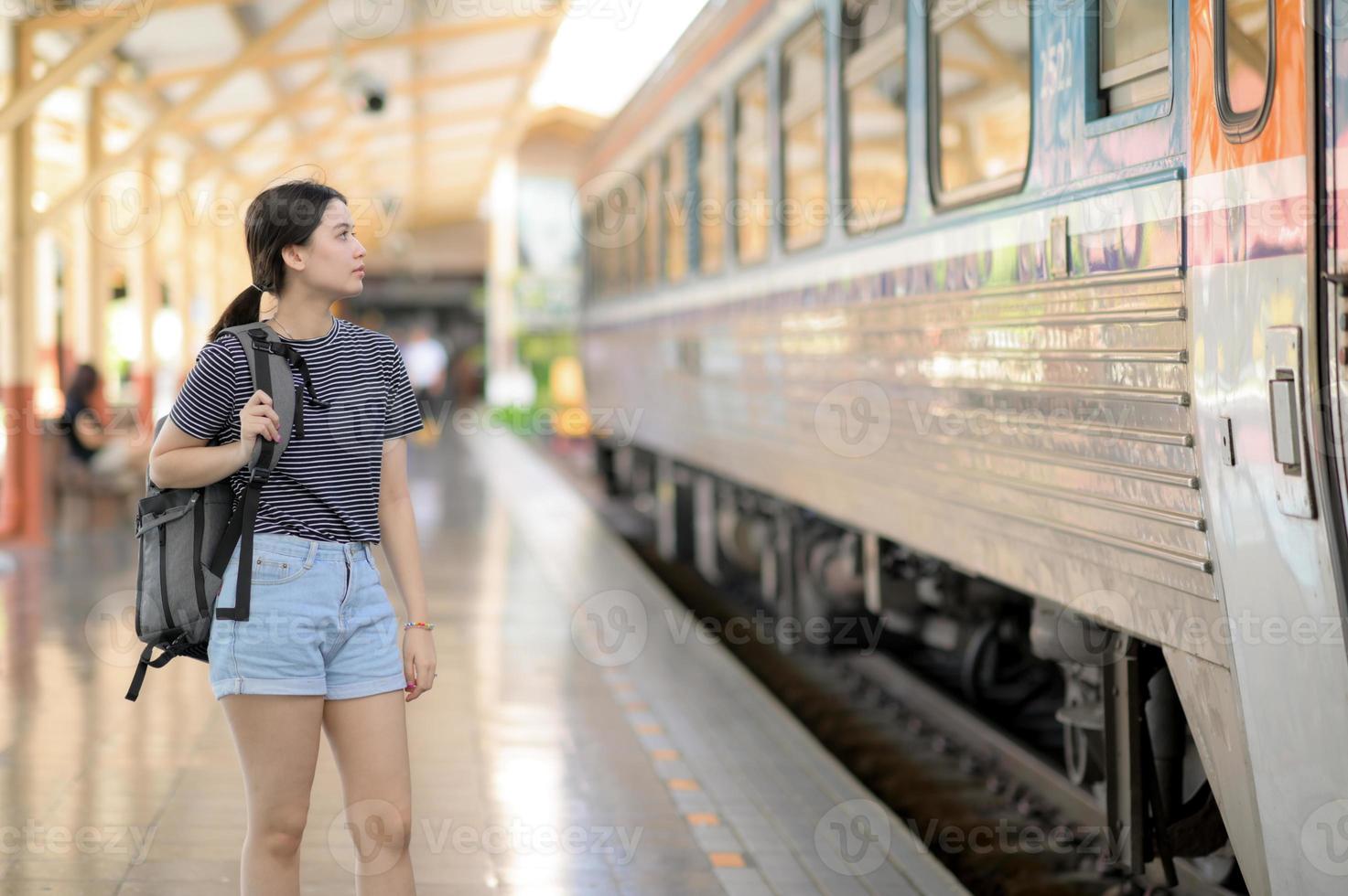 una viaggiatrice internazionale con uno zaino attende il treno. foto