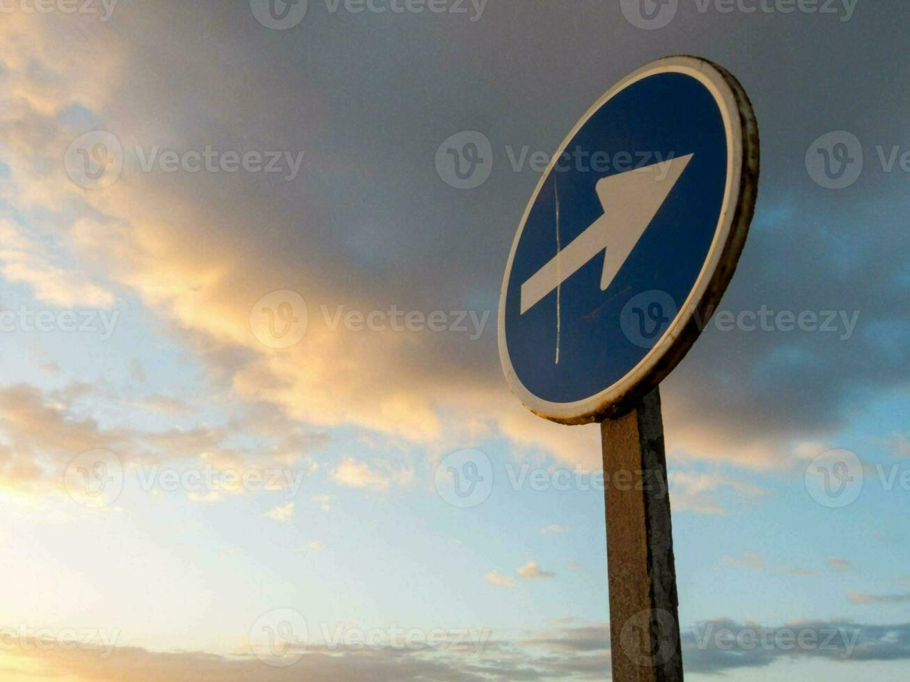 un' blu e bianca cartello con un freccia puntamento nel il direzione di il strada foto