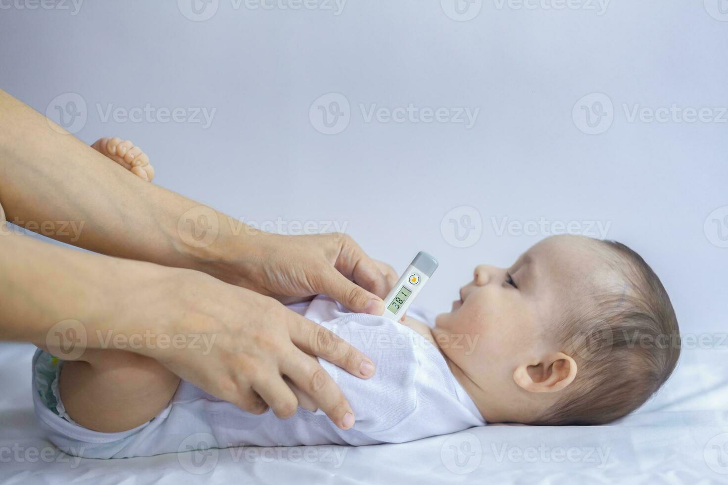 giovane mamma misurazione temperatura di piccolo malato ragazzo. utilizzando termometro per prendere del bambino temperatura ascellare. un' termometro mostrando alto gamma di capretto temperatura - al di sopra di 38 gradi foto