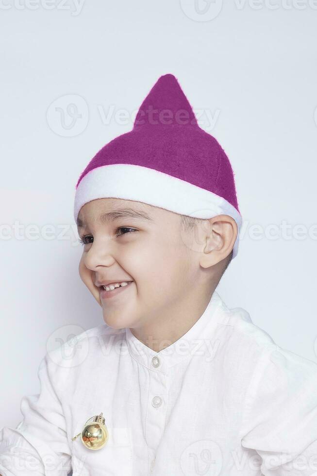 ritratto di un' sei anni ragazzo contro il bianca sfondo. festeggiare Natale. 6-7 anno vecchio ragazzo con Santa cappello. foto