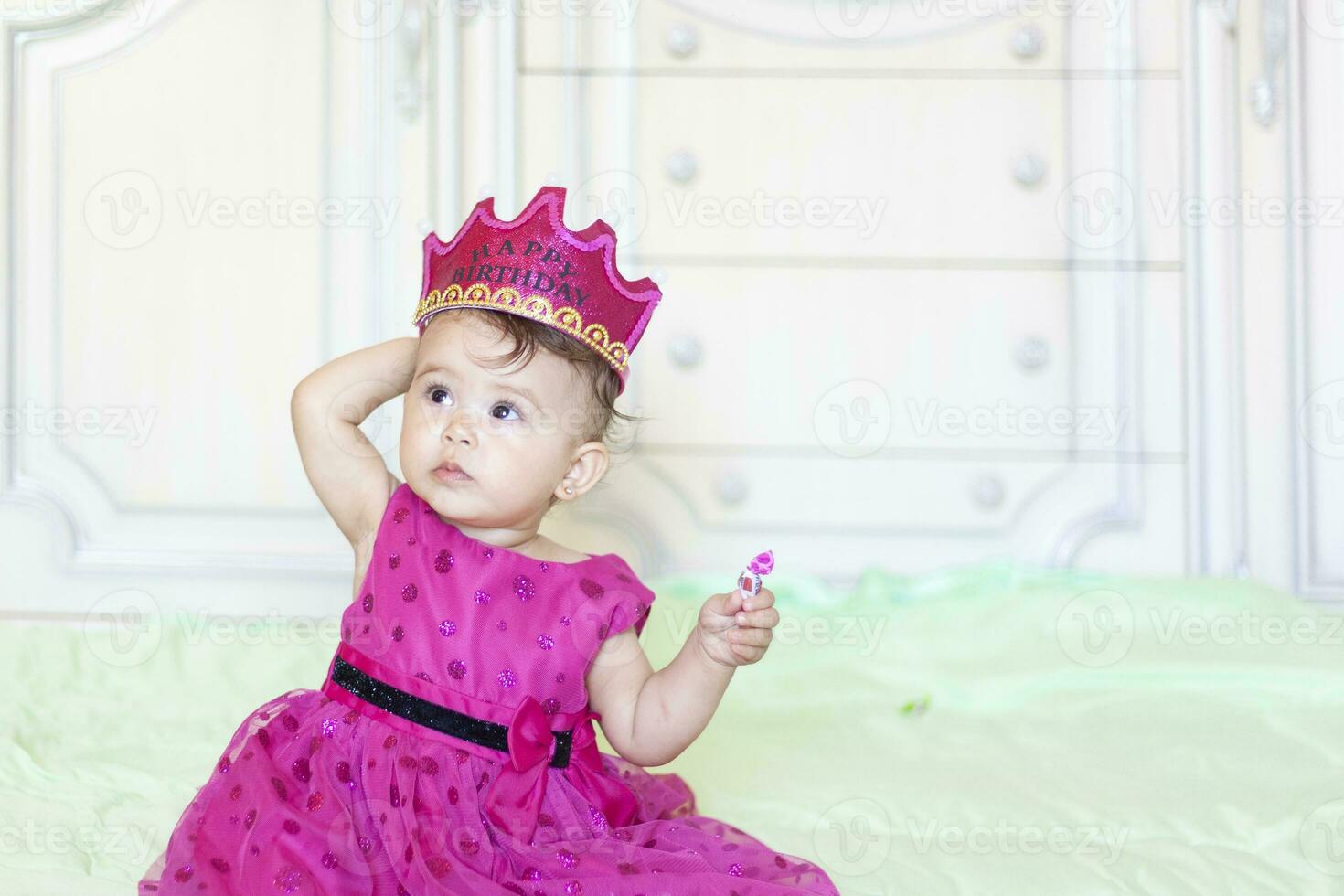 primo compleanno. poco allegro bambino ragazza con corona festeggiare sua primo compleanno festa foto