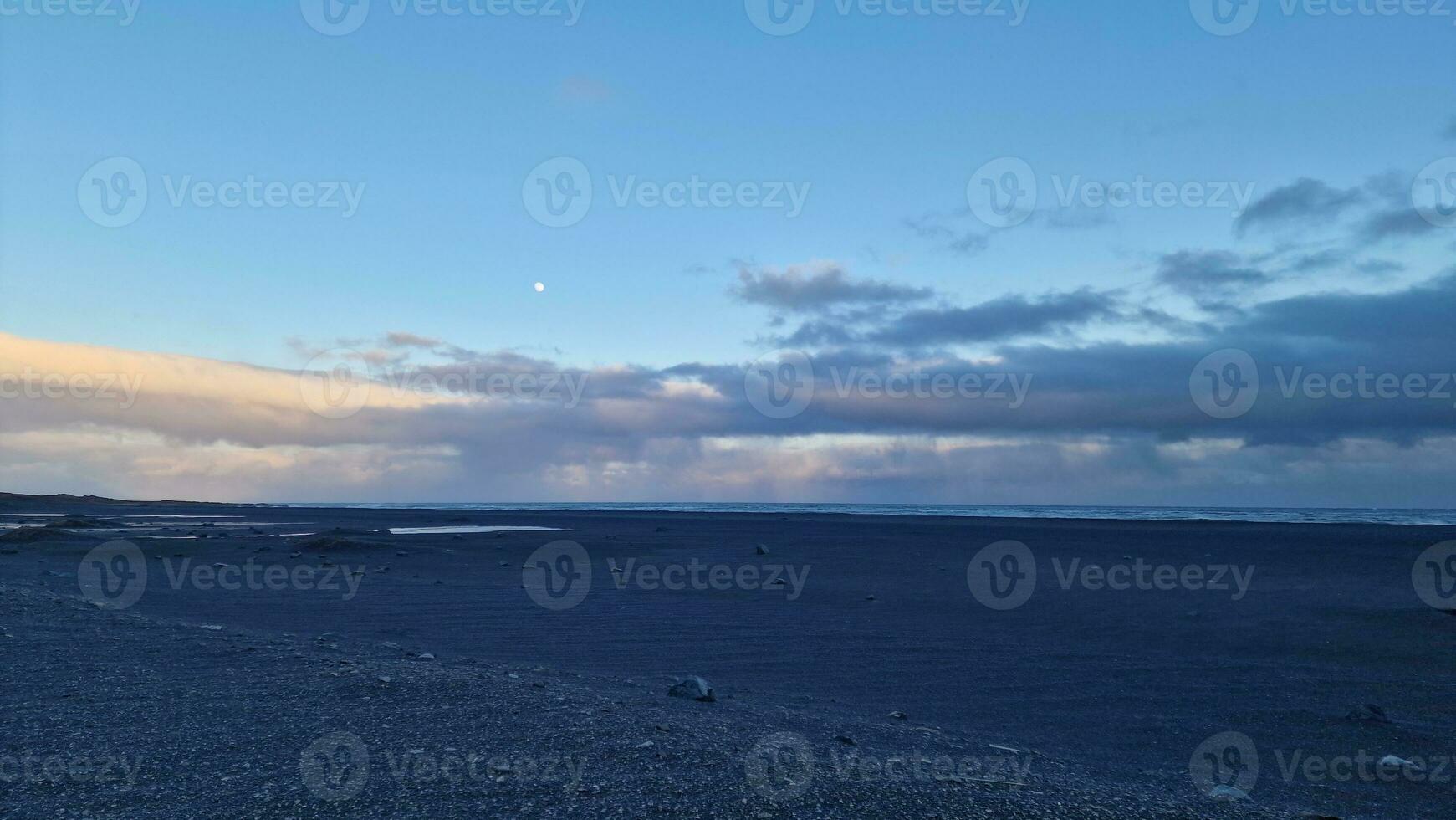 islandese nero sabbia spiaggia a tramonto con d'oro rosa cielo e gelido i campi offerta magico paesaggio. settentrionale regione con enorme oceano davanti costa nel fantastico ambiente. foto