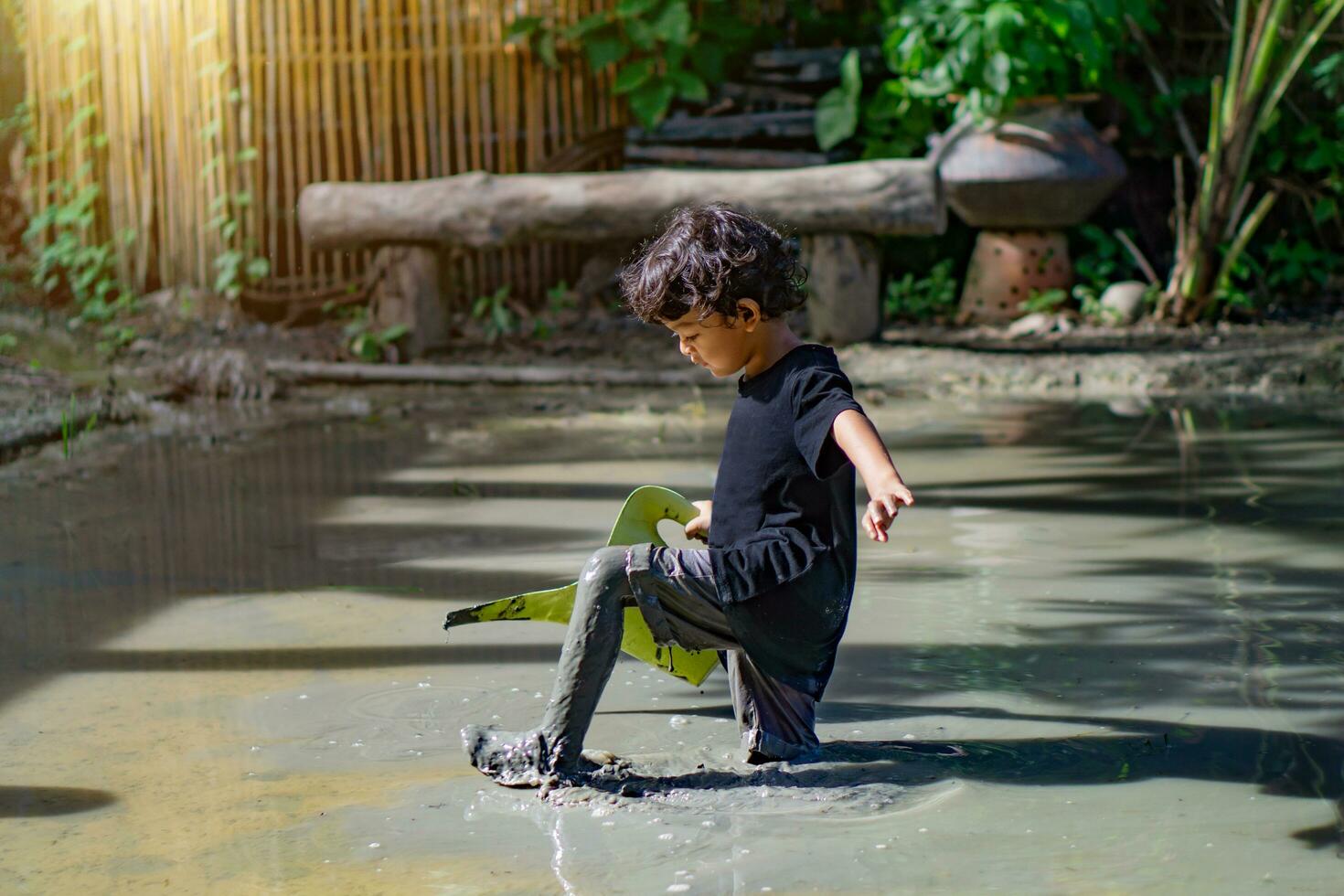 asiatico ragazzo giocando con fango nel un' divertimento posto dentro un' fango fossa costruito per bambini per giocare insieme. foto