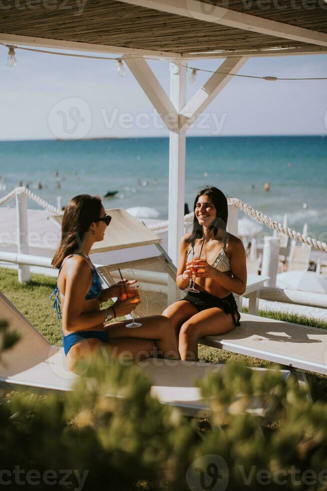 sorridente giovane donne nel bikini godendo vacanza su il spiaggia foto