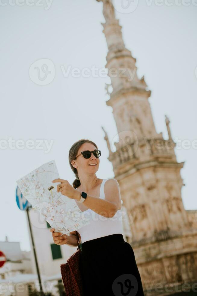 femmina turista con città carta geografica di il santo oronzo statua nel Ostuni, Italia foto