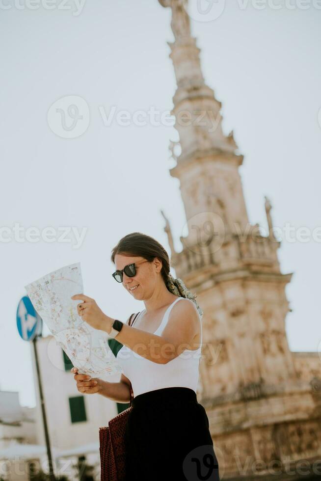 femmina turista con città carta geografica di il santo oronzo statua nel Ostuni, Italia foto