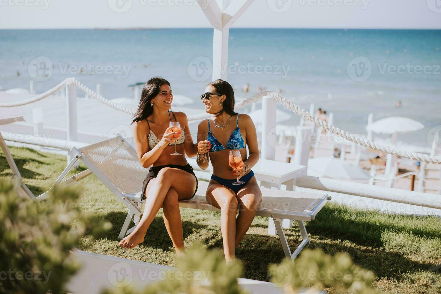 sorridente giovane donne nel bikini godendo vacanza su il spiaggia foto