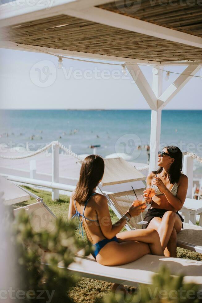 sorridente giovane donne nel bikini godendo vacanza su il spiaggia foto