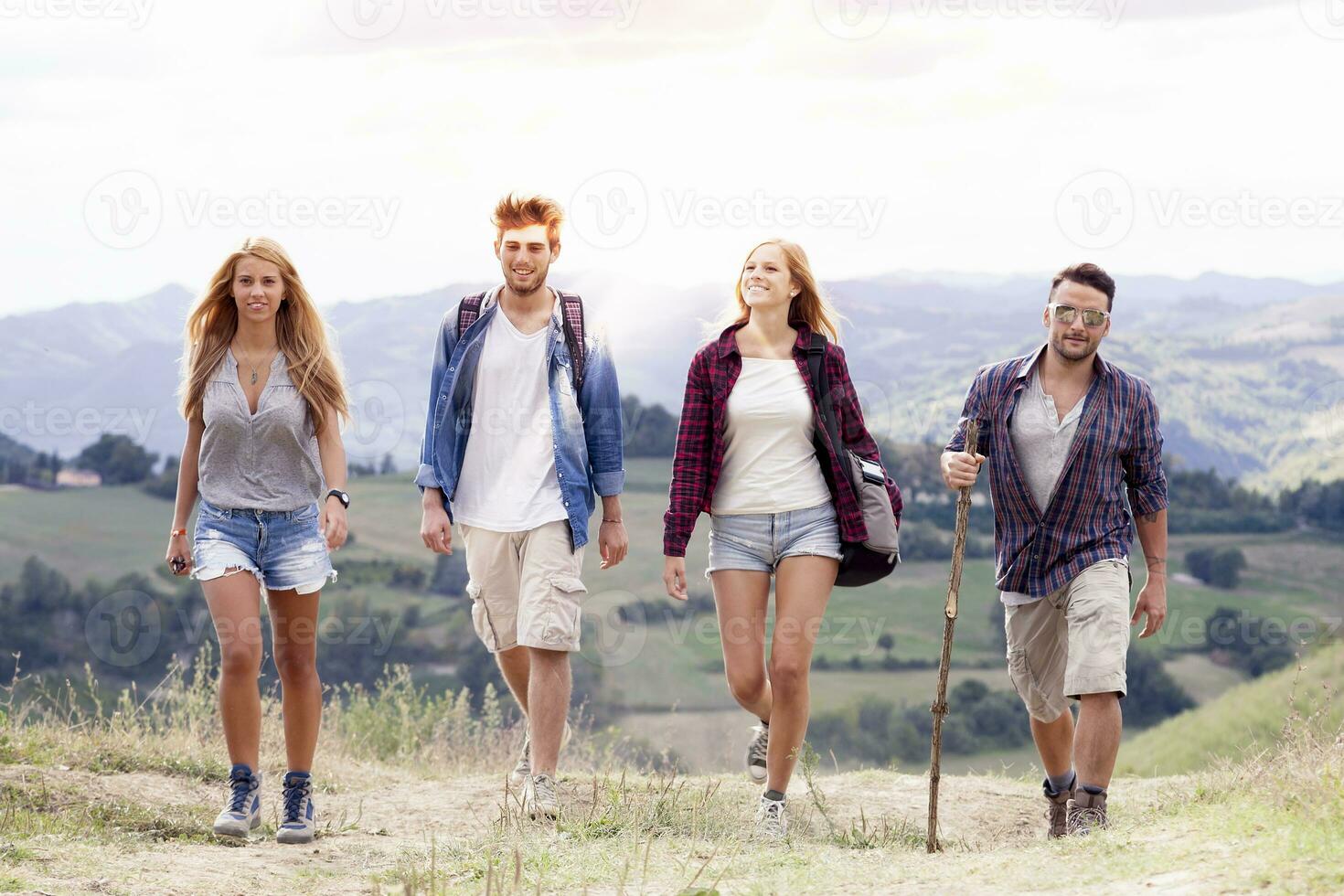 gruppo di giovane escursionisti a piedi verso il orizzonte al di sopra di il montagna foto