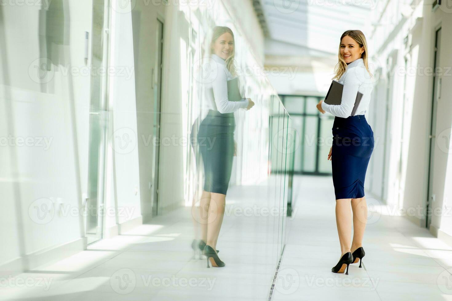 giovane donna con digitale tavoletta a piedi nel il moderno ufficio corridoio foto