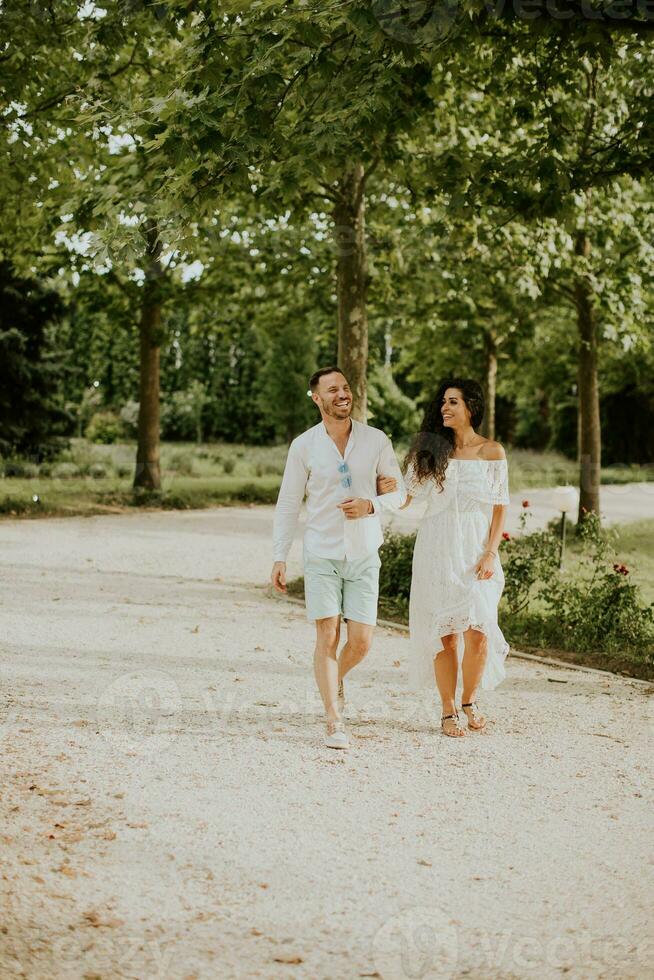 un' contento giovane coppia è godendo il bellissimo dintorni di un' giardino, crogiolarsi nel il sole e ogni altri azienda foto