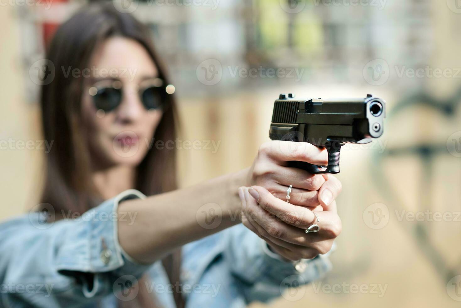 giovane ragazza con un' pistola nel il suo mani spara nel natura foto