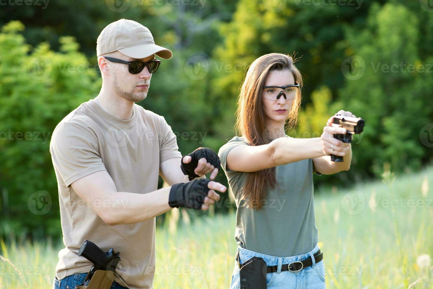 un' ragazza impara per sparare un' pistola con un istruttore a il formazione terra foto