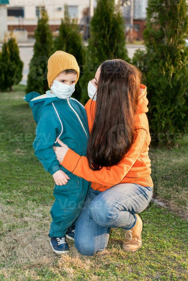 un' madre e un' bambino nel medico maschere camminare su il strada durante il coronavirus e covid-19 pandemia. foto