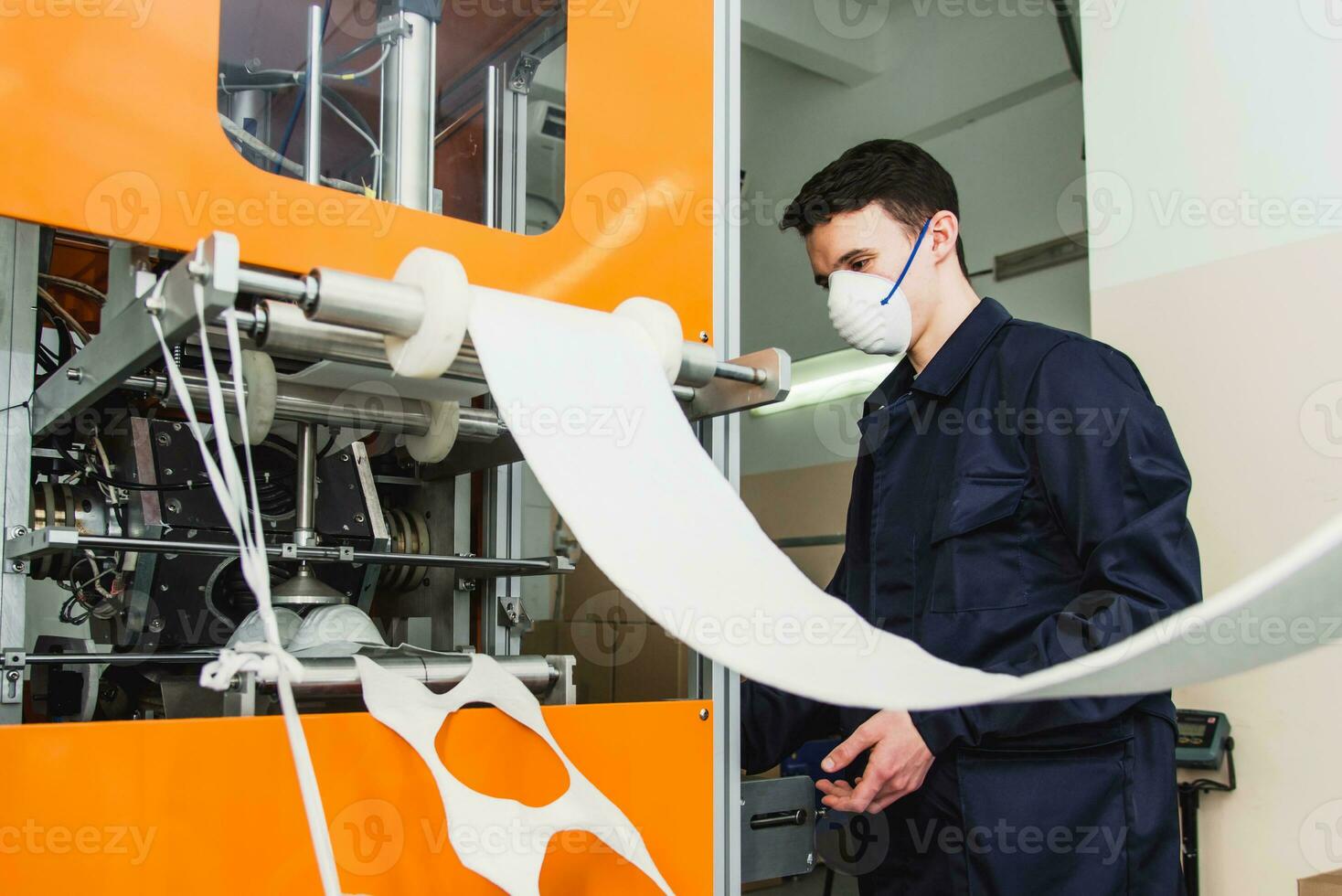 un' lavoratore sta a il macchina nel un' fabbrica per il produzione di medico maschere con nanofibra. coronovirus e covid-19 protezione foto