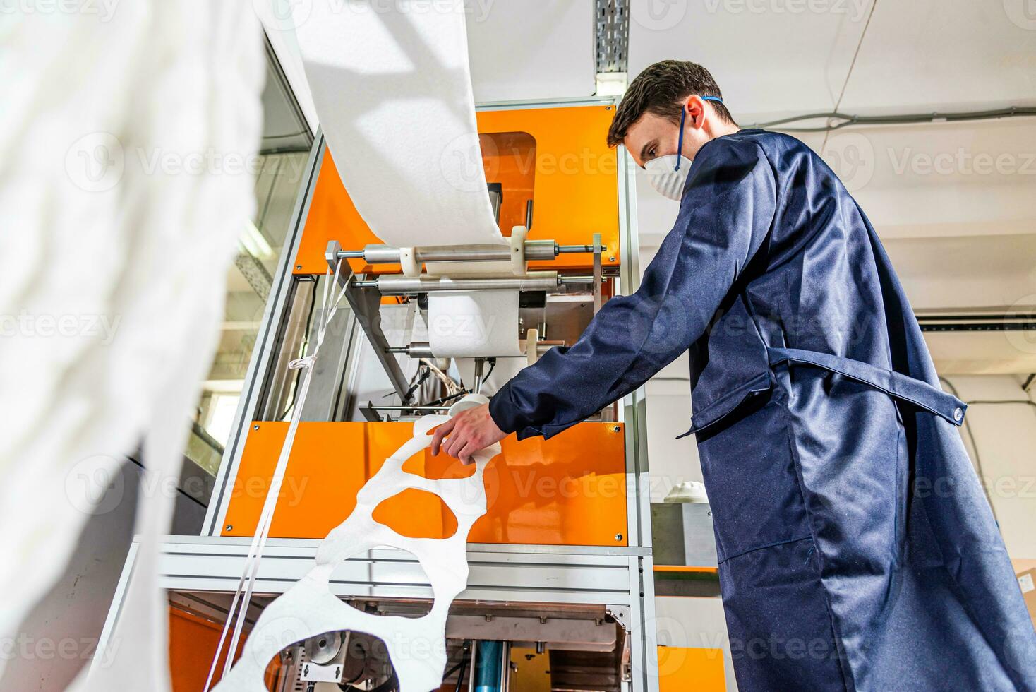 un' lavoratore sta a il macchina nel un' fabbrica per il produzione di medico maschere con nanofibra. coronovirus e covid-19 protezione foto