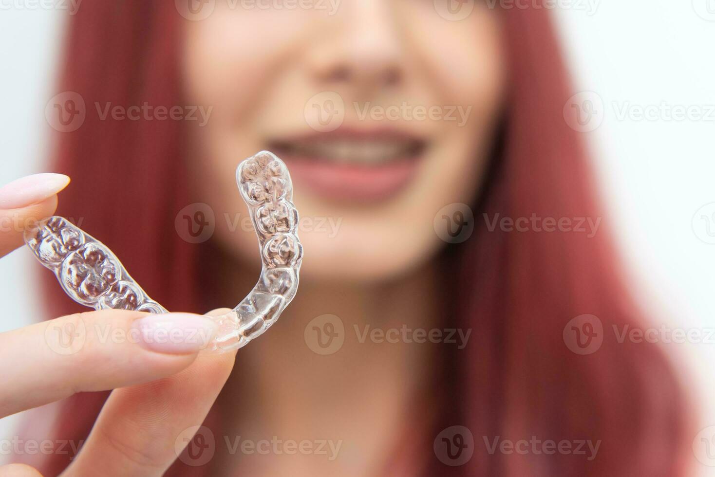 un' donna con un' bellissimo Sorridi detiene allineatori nel sua mano foto