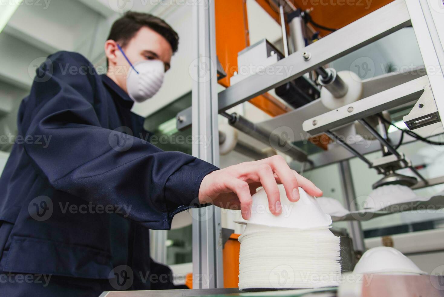 un' lavoratore sta a il macchina nel un' fabbrica per il produzione di medico maschere con nanofibra. coronovirus e covid-19 protezione foto