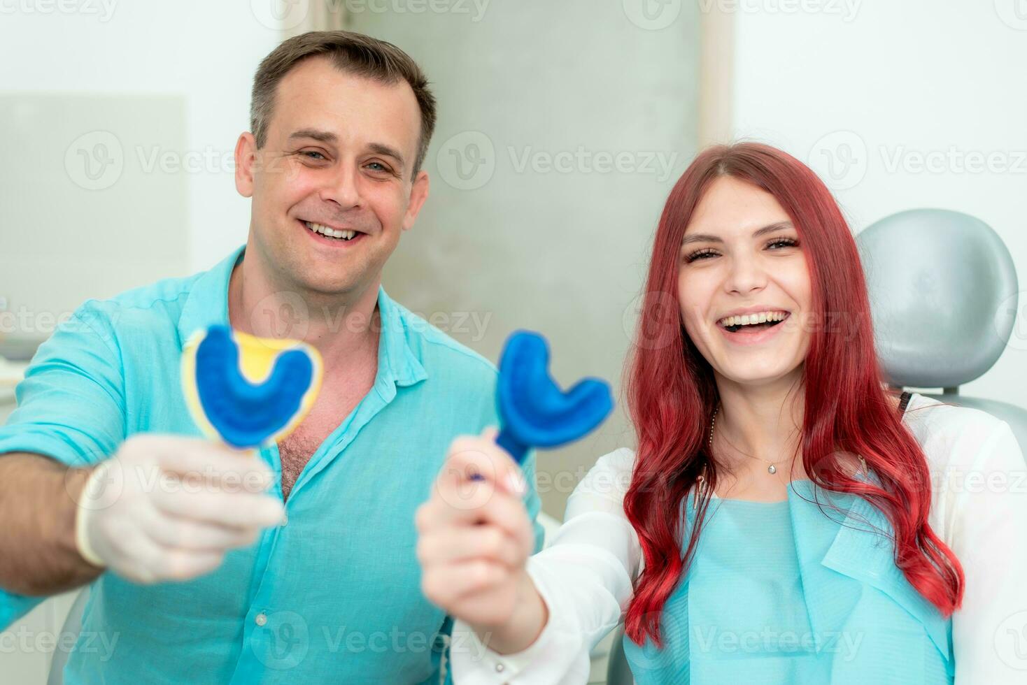 contento medico dentista con il suo paziente mostrare il risultato di impressioni di sua denti su un' cucchiaio con silicone Materiale foto