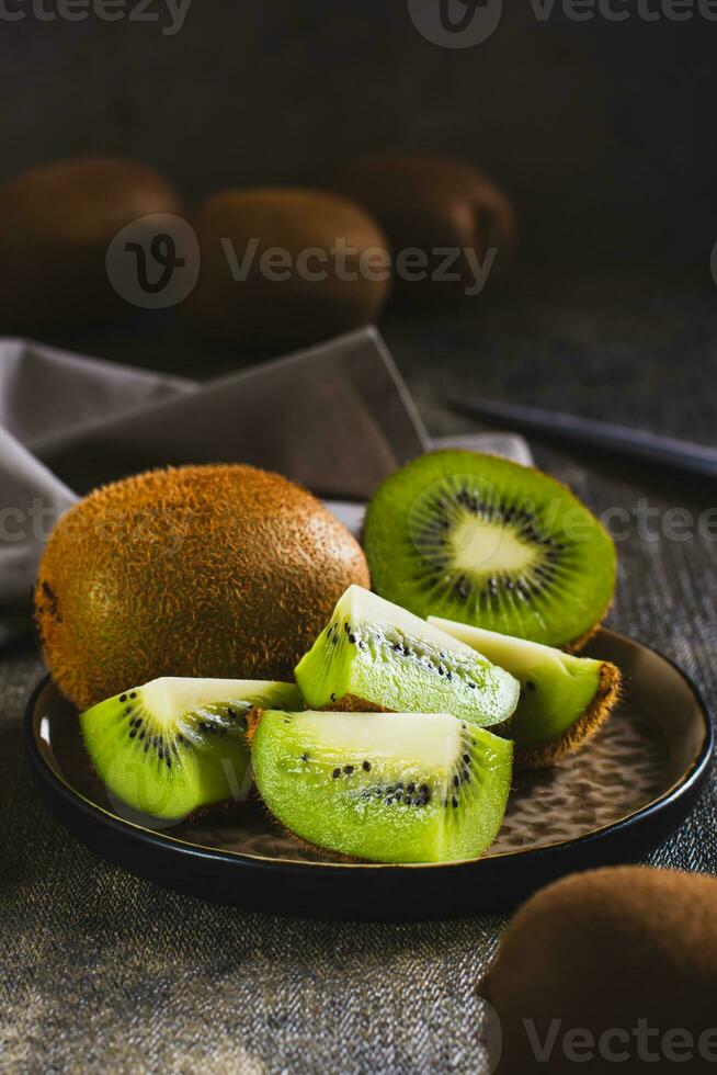 fresco maturo affettato Kiwi frutta su un' piatto su il tavolo verticale Visualizza foto